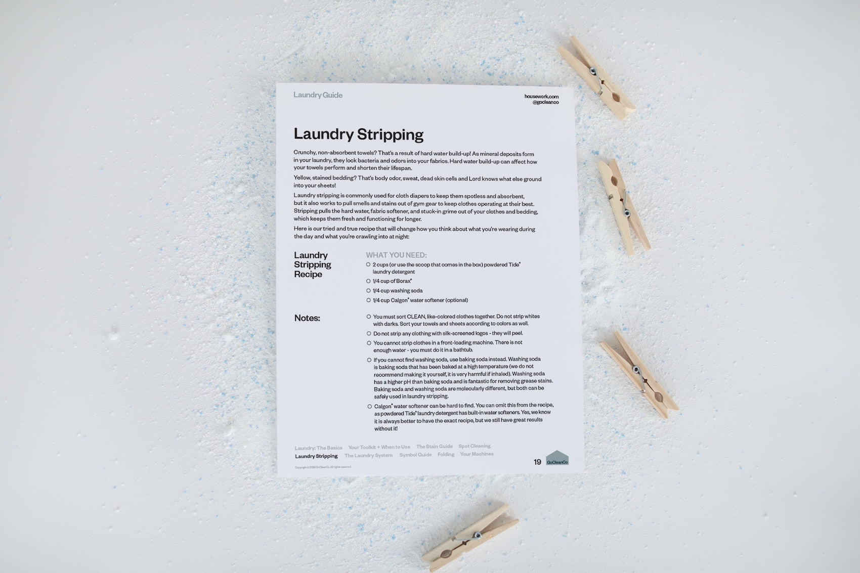 The laundry stripping page of the GoCleanCo Laundry Guide is on a white background next to clothes pins.