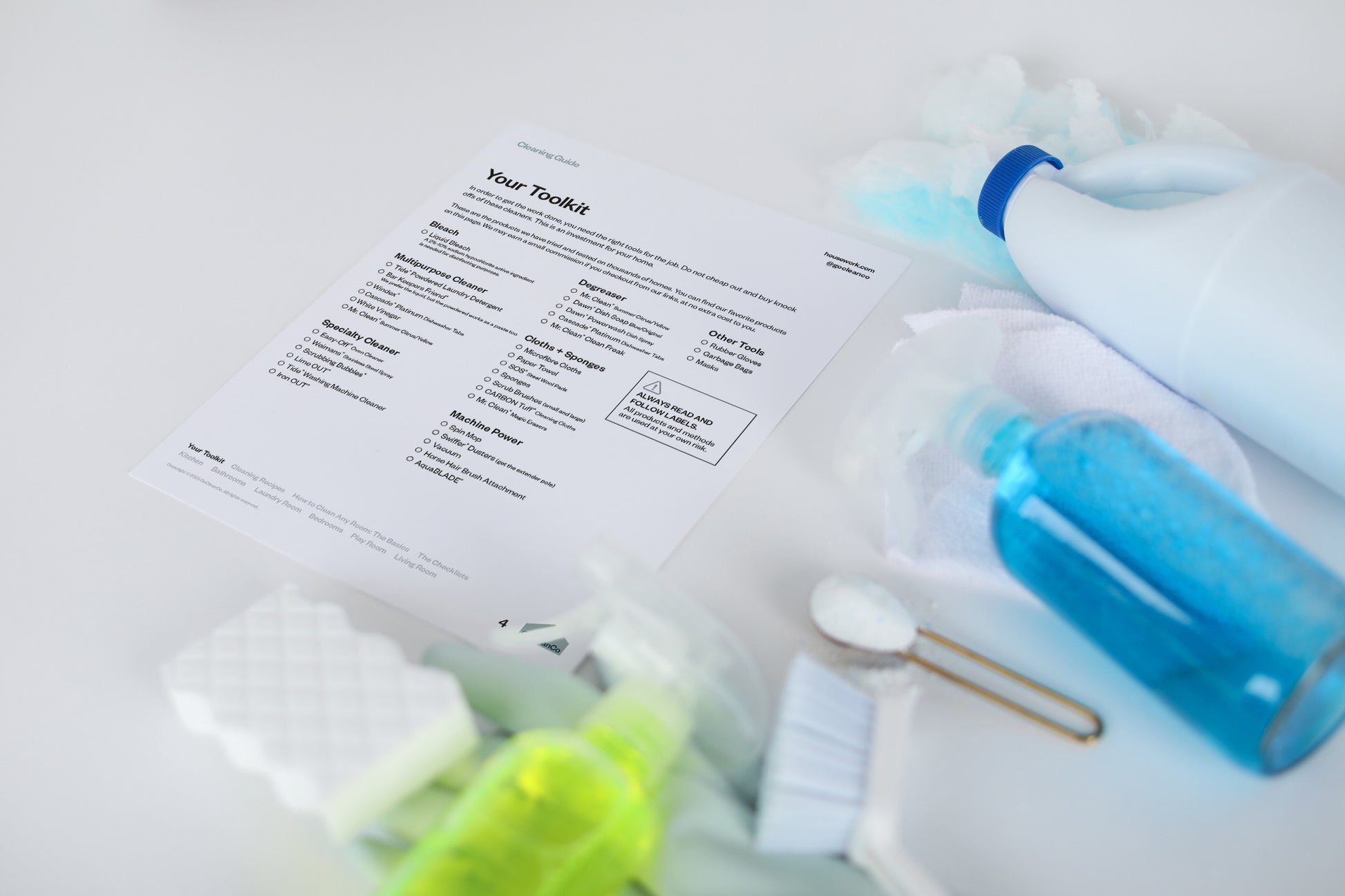 The toolkit page of the GoCleanCo Cleaning Guide is next to cleaning supplies.