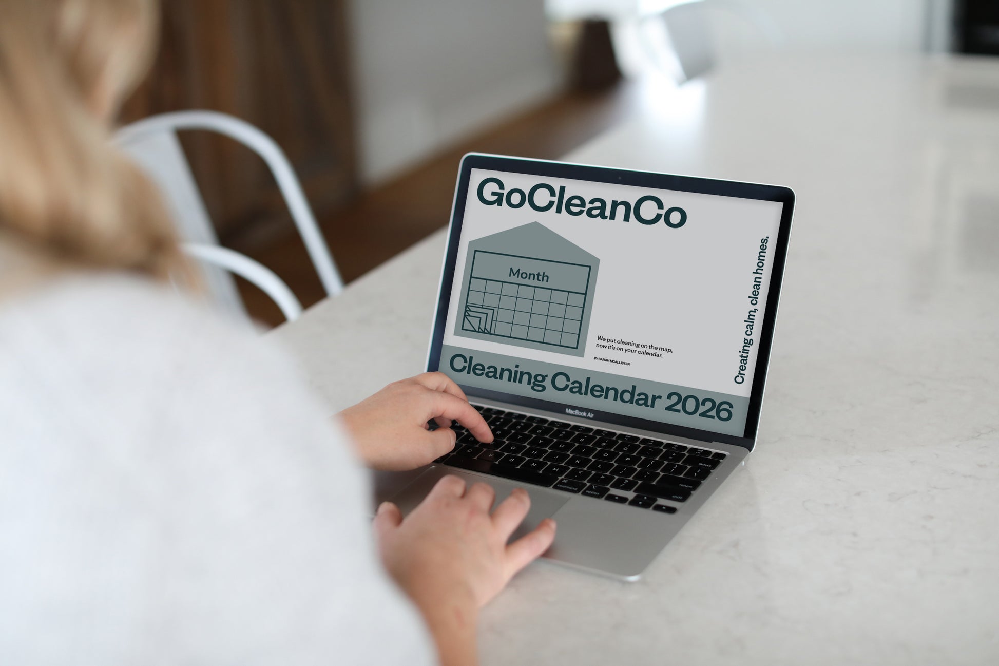 Person using a laptop with a GoCleanCo cleaning calendar displayed on the screen.
