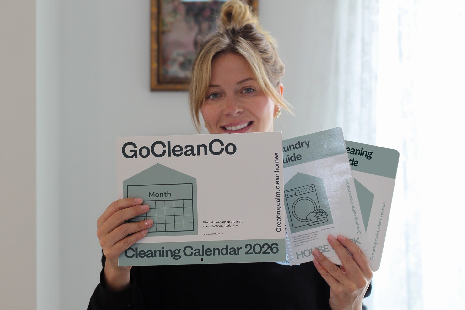 Person holding a GoCleanCo cleaning calendar,  laundry guide and cleaning guide.