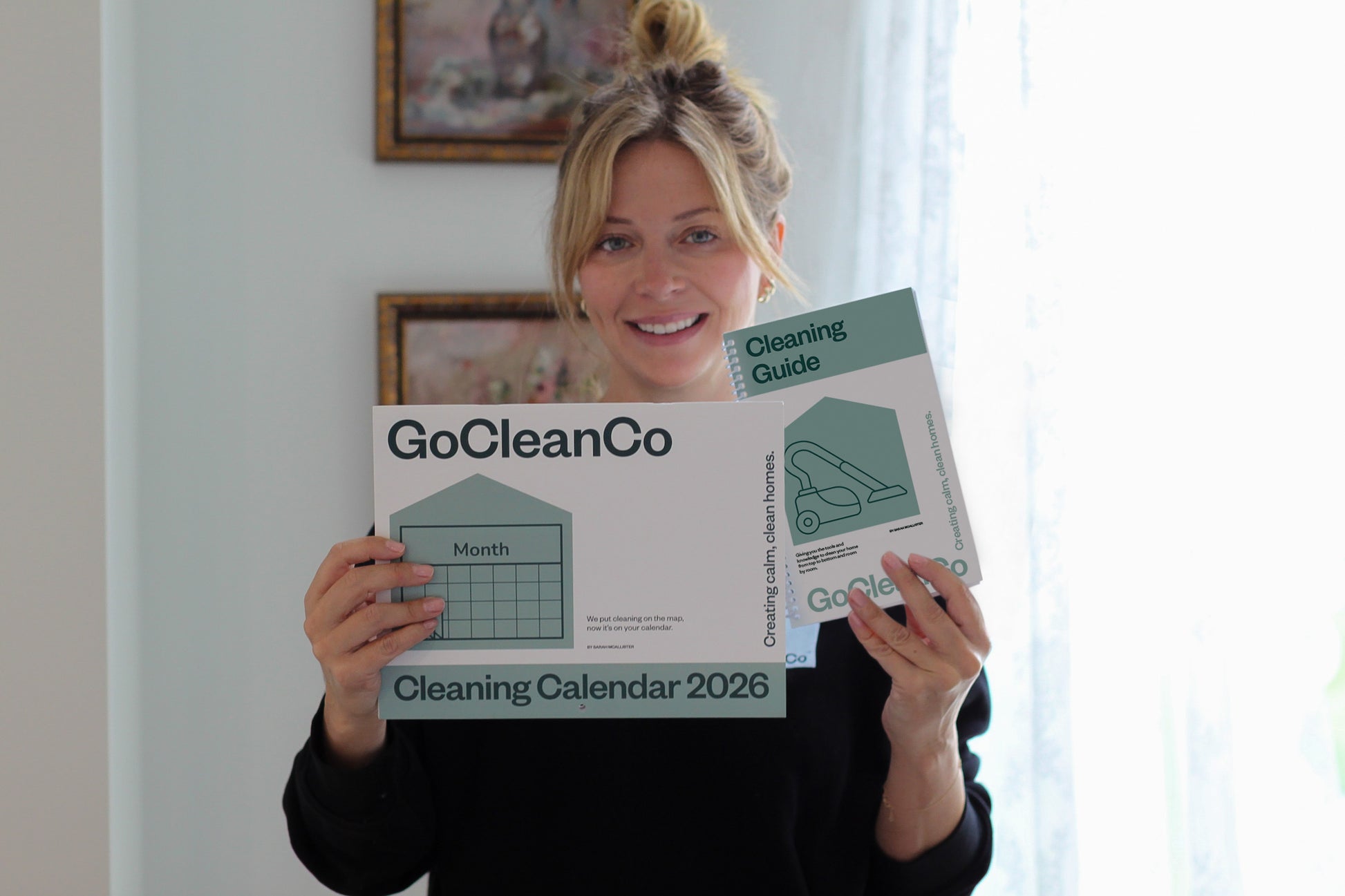 Woman holding a GoCleanCo cleaning calendar and cleaning guide