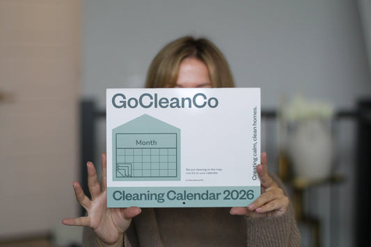 Person holding a GoCleanCo cleaning calendar 2022 in front of their face.