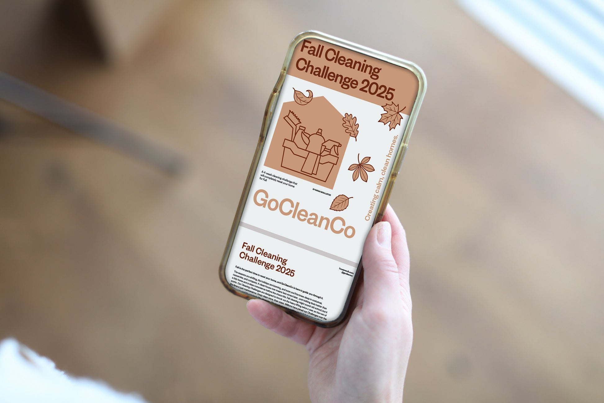 A hand holds a smartphone displaying the GoCleanCo "Fall Cleaning Challenge 2025" on its screen.