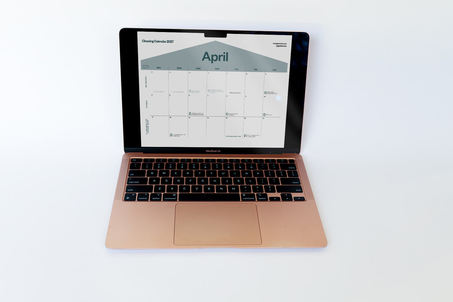 A rose gold Apple MacBook laptop is open and centered on a clean white background, displaying a digital cleaning calendar on its screen.