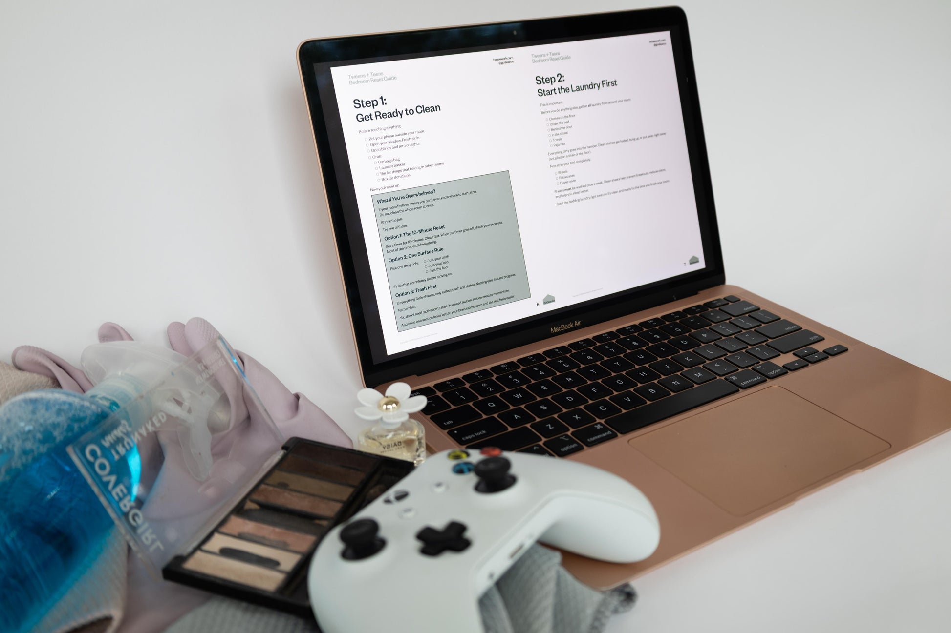 Laptop on a desk with a cleaning product, gloves, and a controller.