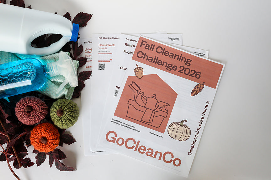 A styled flat-lay of cleaning products and a printed guide. The guide reads 'Fall Cleaning Challenge 2026' with the GoCleanCo logo.