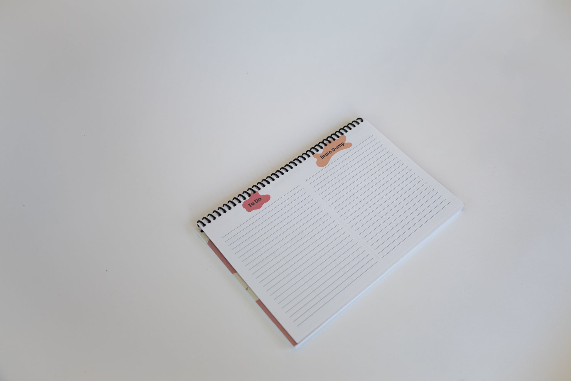 A spiral-bound lined notepad with to do and brain dump columns on a plain white background.